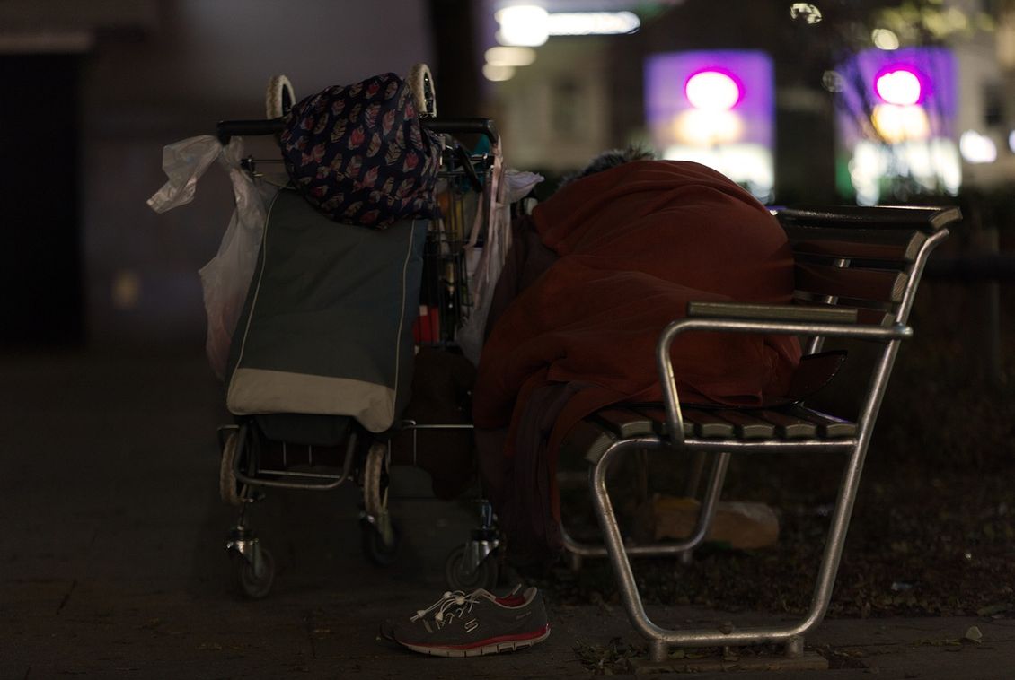 Person schläft unter einem Schlafsack auf einer Bank
